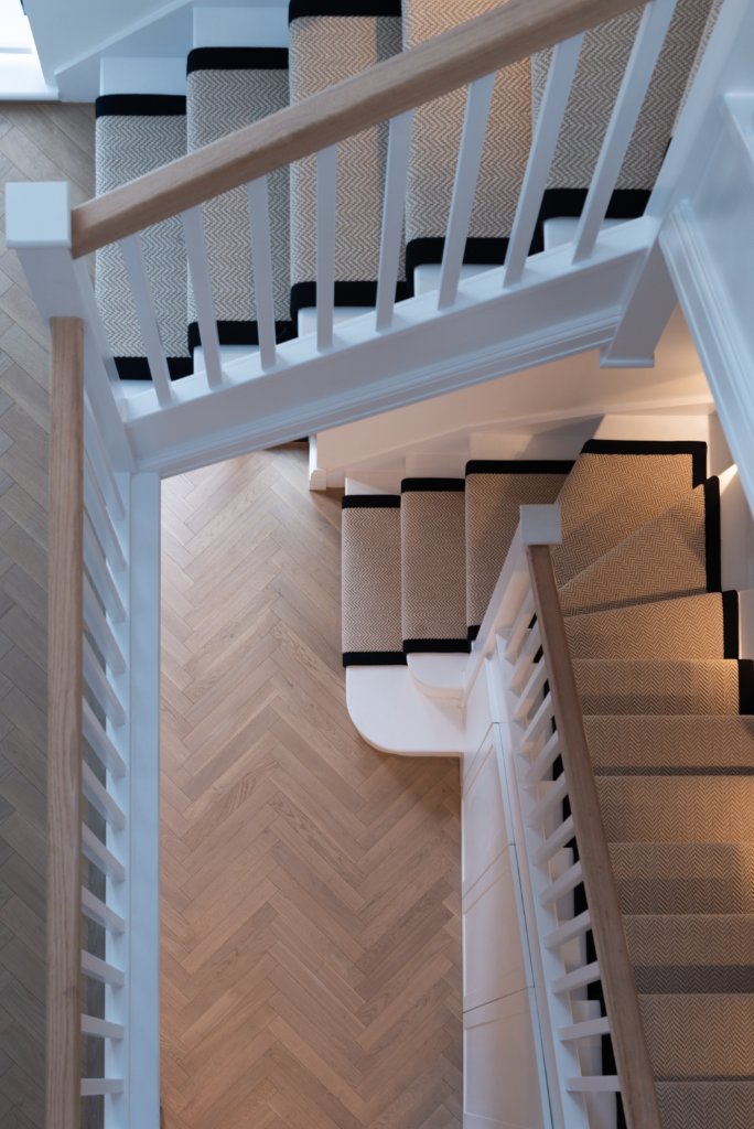 Alfold Gardens staircase detail with herringbone flooring and elegant bannister — interior by Ademchic