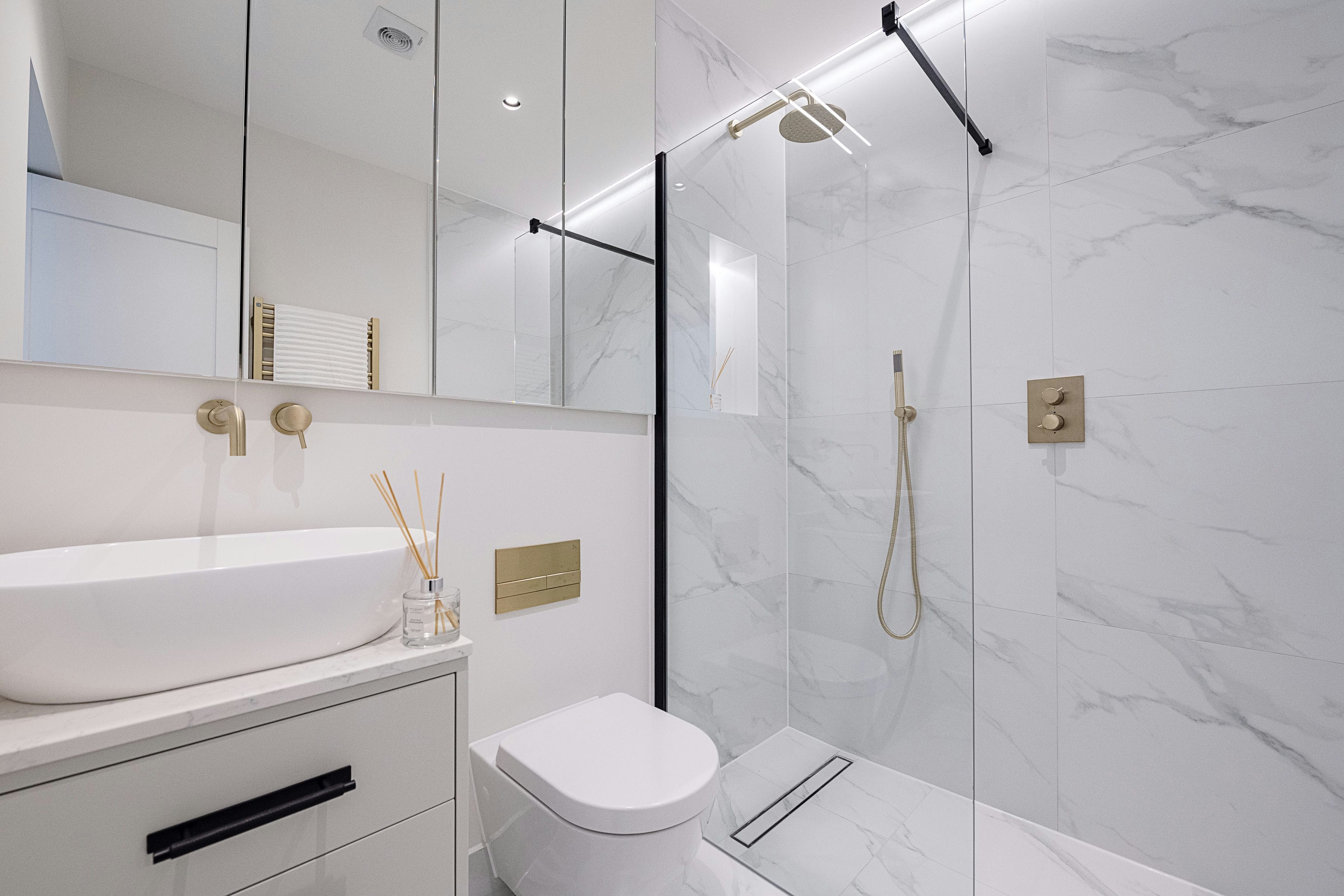 The Rosemont bathroom with marble wall tiles, walk-in shower and brass fittings &mdash; interior design by Ademchic