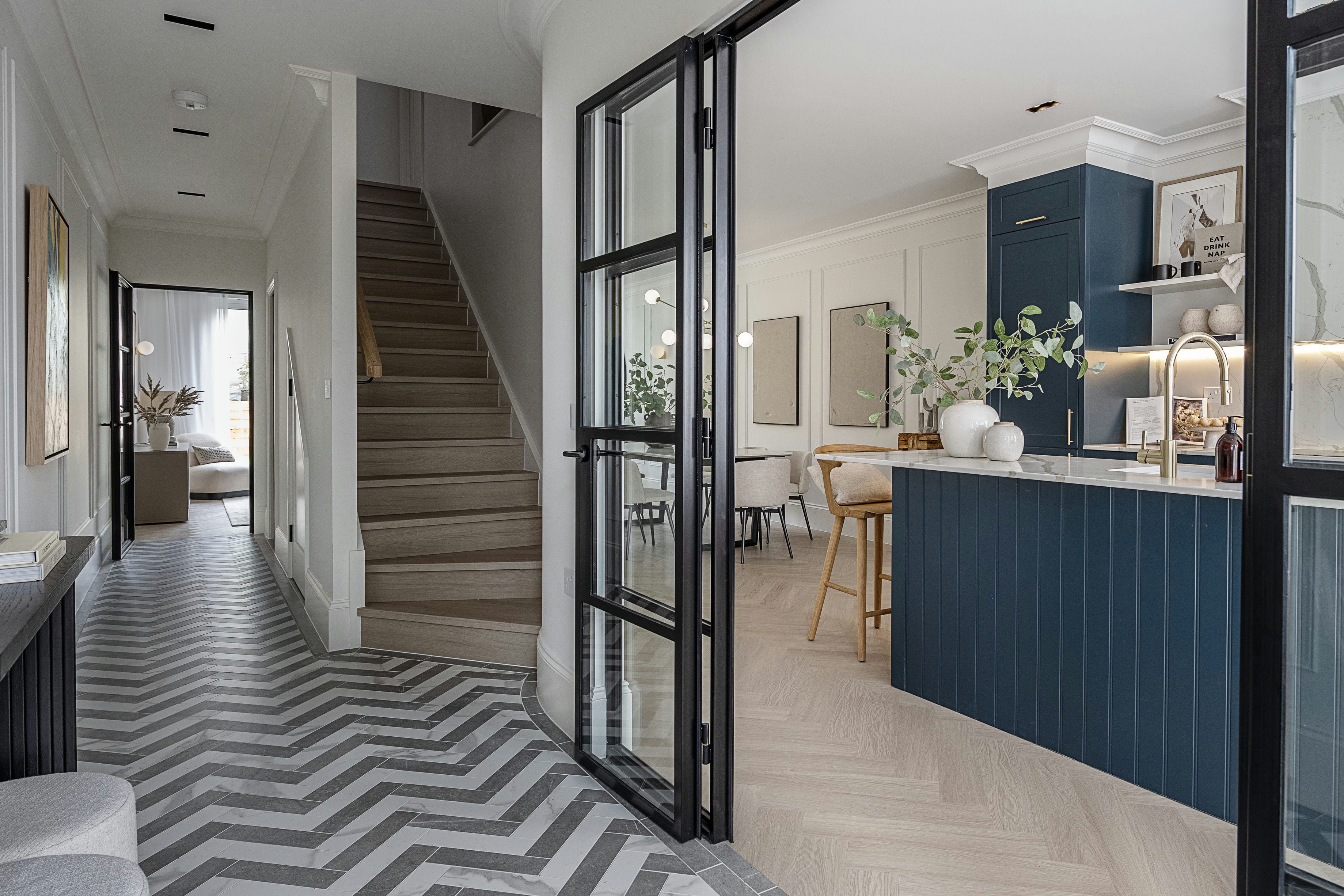 The Rosemont entrance hallway with Crittall partition, chevron marble tiles and kitchen beyond &mdash; interior design by Ademchic