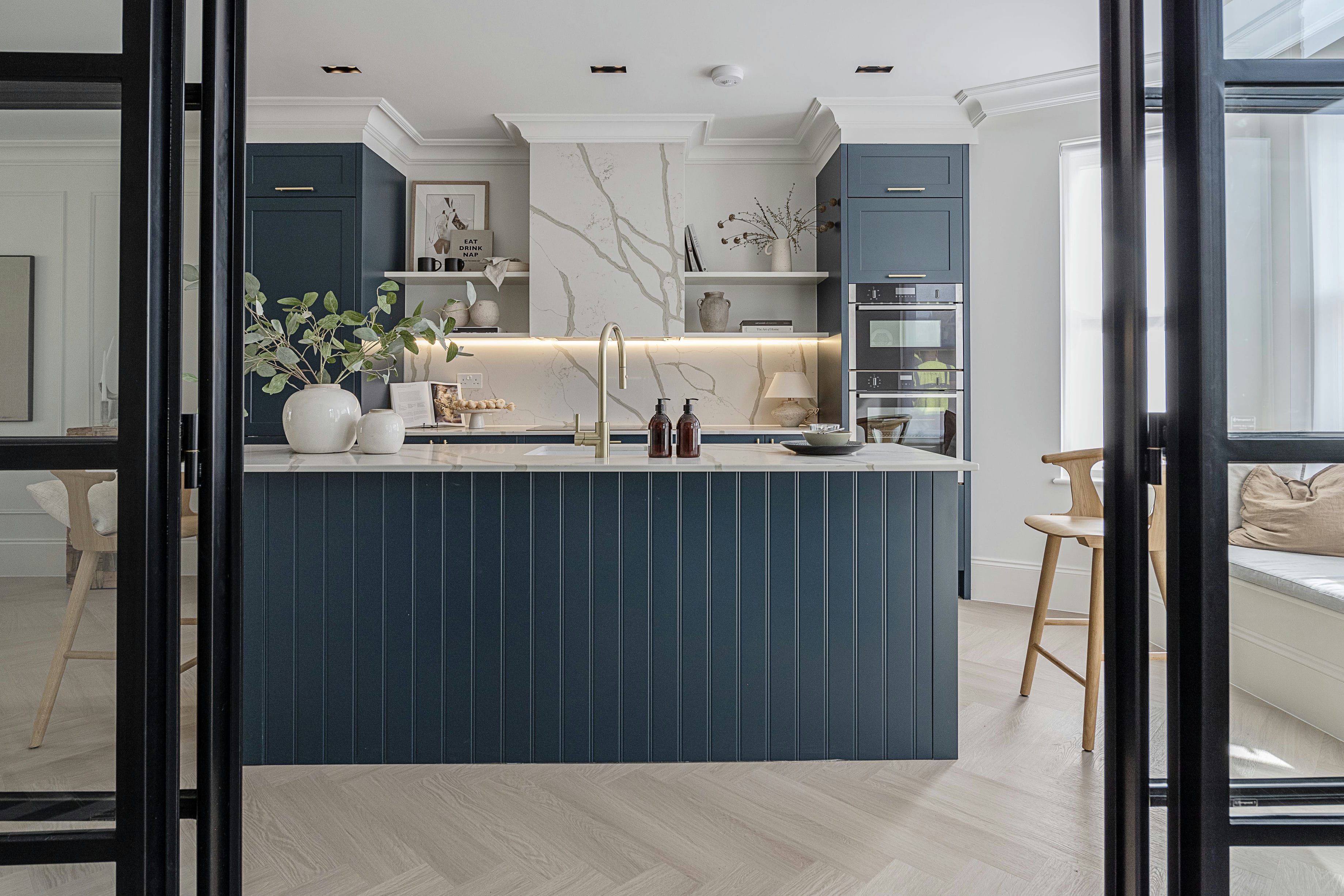 The Rosemont kitchen with blue fluted island, marble backsplash seen through Crittall doors &mdash; designed by Ademchic