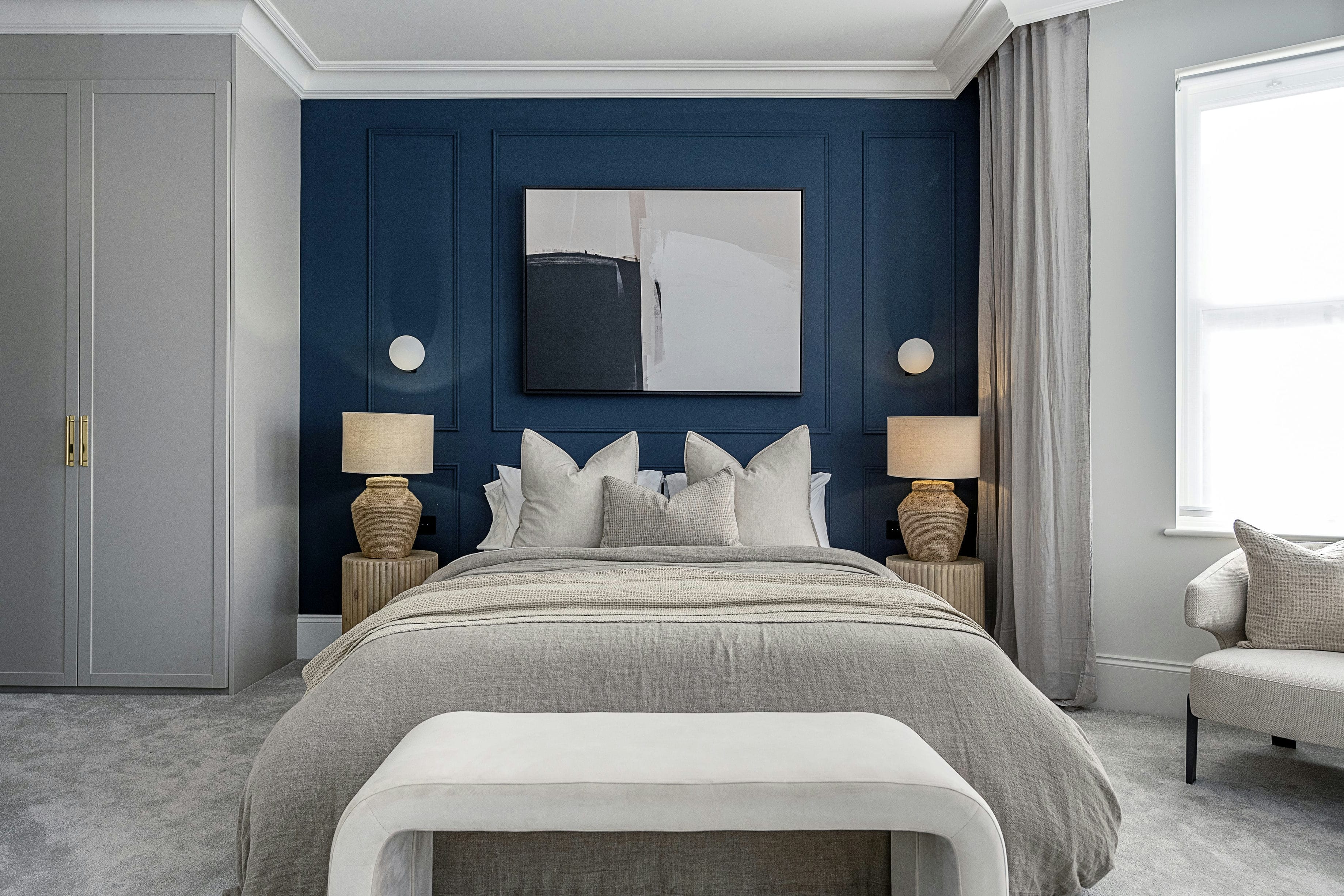 The Rosemont primary bedroom with dark blue panelled wall, built-in wardrobes and artwork &mdash; interior design by Ademchic