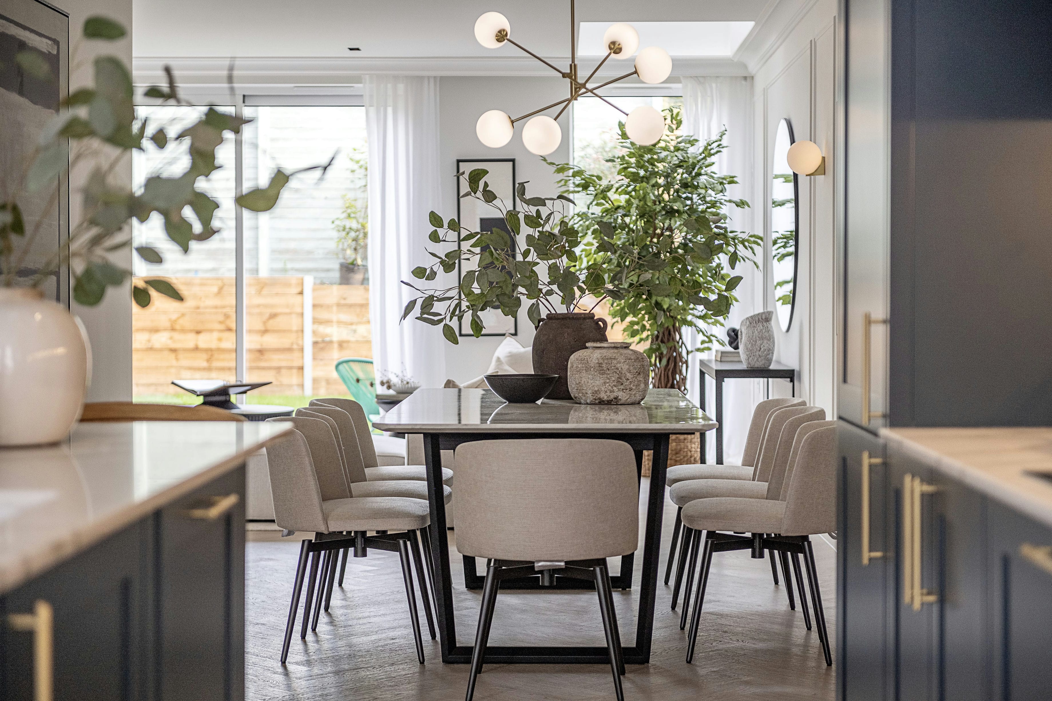 The Rosemont dining area with pendant lighting, blue kitchen cabinetry and garden view &mdash; interior design by Ademchic